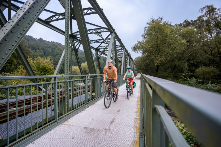 Zwei Radfahrer fahren über eine alte Eisenbahnbrücke auf dem Chemnitztalradweg.