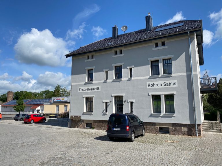 Zu sehen ist ein saniertes Bahnhofsgebäude. Es wird heute als Wohn- und Geschäftshaus genutzt.