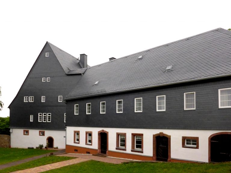 Zu sehen ist das Pfarrhaus Wiederau, dessen Außenfassade frisch saniert wurde.