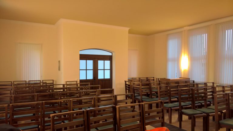 Zu sehen ist der Innenraum der Trauerhalle Wiederau, der für eine Trauerfeier bestuhlt ist.