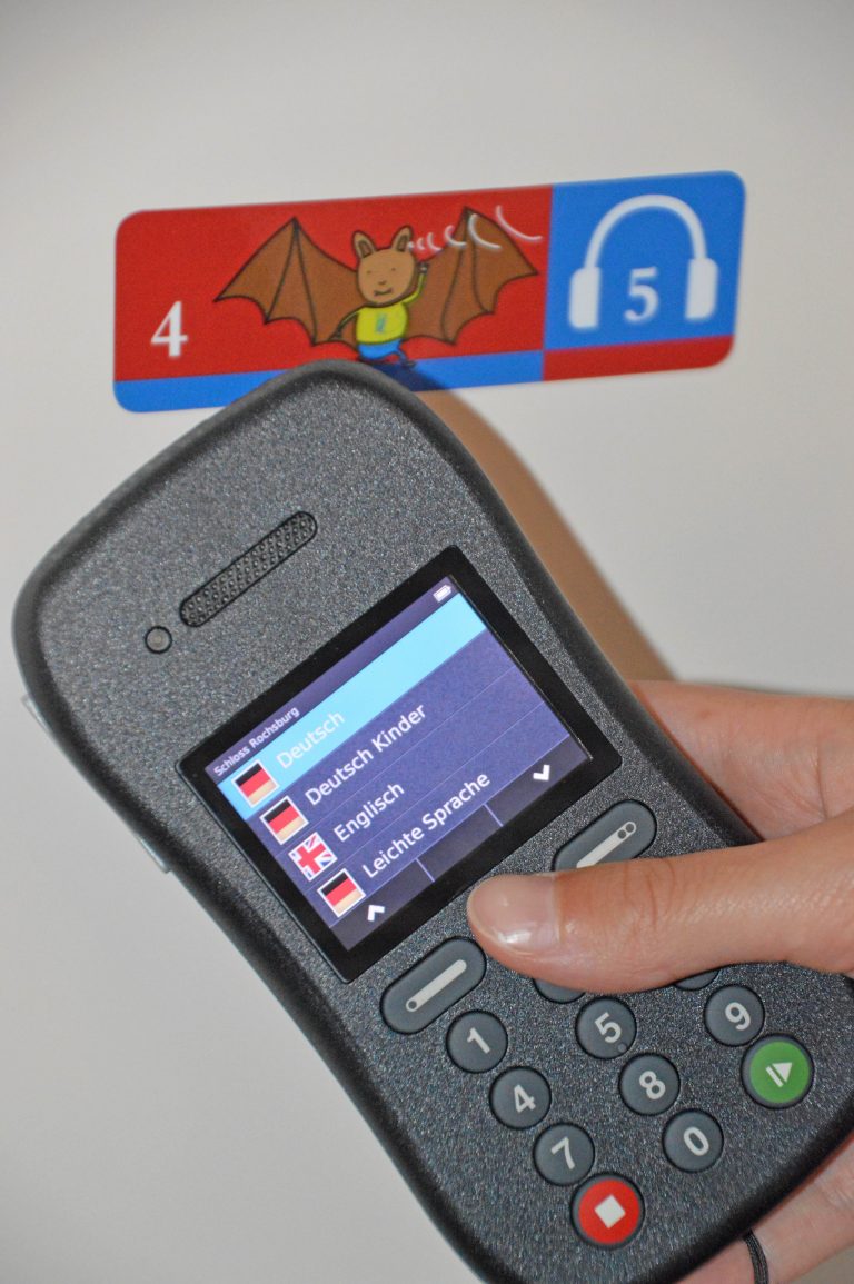 Das Foto zeigt eine Hand, die einen der Audioguides festhält.