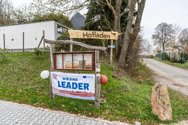 Zu sehen ist ein Banner mit der Aufschrift "Wir sind LEADER". Das soll verdeutlichen, dass das Projekt gefördert wurde. Das Banner hängt am Eingang zu einem Hofladen.